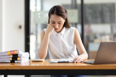 Yorgun ve Asyalı bir kadının portresi ofiste vergi bilgisayarıyla çalışıyor. Üzgün, mutsuz, endişeli, depresyon ya da çalışan hayatı stres konsepti