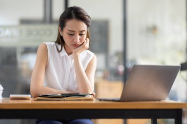Yorgun ve Asyalı bir kadının portresi ofiste vergi bilgisayarıyla çalışıyor. Üzgün, mutsuz, endişeli, depresyon ya da çalışan hayatı stres konsepti