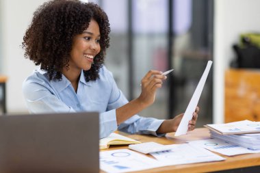 Başarılı Afro-Amerikan muhasebeci kadın ofisteki dizüstü bilgisayardan evrak vergisi alıyor. Yatırım ekonomisi ve pazarlama araştırma kavramını finanse et.