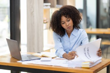 Başarılı Afro-Amerikan muhasebeci kadın ofisteki dizüstü bilgisayardan evrak vergisi alıyor. Yatırım ekonomisi ve pazarlama araştırma kavramını finanse et.
