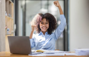 Heyecanlı mutlu Asyalı Afrikalı kadın dizüstü bilgisayara bakıyor, online galibiyeti kutluyor, neşeli genç Afrikalı kız sevinçten çığlık atıyor, bir ofis arka planında izole edilmiş.