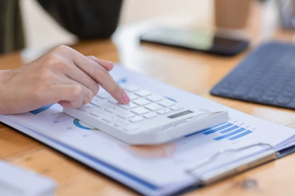 Neşeli Asyalı iş kadını çalışma alanı ofisinde çalışıyor. Ofisteki ahşap masada matematik finansmanı yapmak, vergi, muhasebe, finansal konsebe.