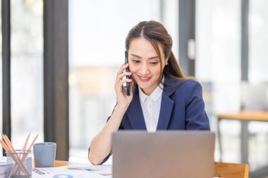 İş yerinde dizüstü bilgisayarda çalışan Asyalı genç bir iş kadınının çekimleri. İşadamlarının portresi online pazarlama. Telefon e-pazarlama kavramı..