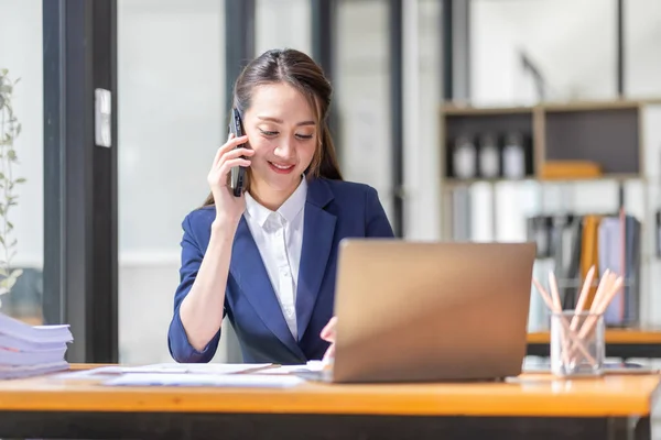 İş yerinde dizüstü bilgisayarda çalışan Asyalı genç bir iş kadınının çekimleri. İşadamlarının portresi online pazarlama. Telefon e-pazarlama kavramı..