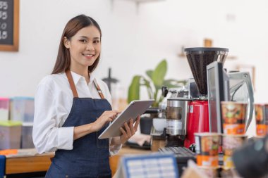 Küçük bir iş kuran, bir bar tezgahının yanında duran önlüklü mutlu Asyalı kadın, küçük işletme sahibi, restoran sahibi, barista, cafe, Online, KME, girişimci ve satıcı konsepti