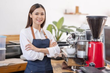 Küçük bir iş kuran, bir bar tezgahının yanında duran önlüklü mutlu Asyalı kadın, küçük işletme sahibi, restoran sahibi, barista, cafe, Online, KME, girişimci ve satıcı konsepti