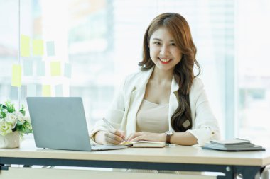 Dizüstü bilgisayarda çalışan gülümseyen Asyalı kadın başarı için mutlu. Ofiste mutlu kadın çalışan ya da etiket metni için kopyalama alanı olan ortak çalışma alanı.