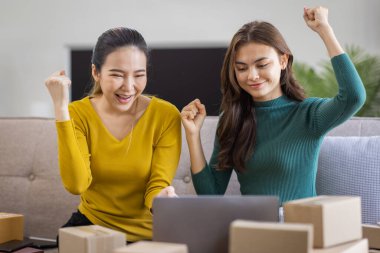 İki Asyalı kadın başlangıç için küçük işletme KOBİ girişimcisi dizüstü bilgisayarda paket kutusuyla evde çalışıyor, çevrimiçi pazarlama paketleme ve KOBİ fikri sunuyor