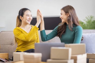 İki Asyalı kadın başlangıç için küçük işletme KOBİ girişimcisi dizüstü bilgisayarda paket kutusuyla evde çalışıyor, çevrimiçi pazarlama paketleme ve KOBİ fikri sunuyor