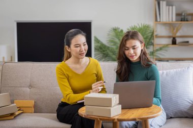 İki Asyalı kadın başlangıç için küçük işletme KOBİ girişimcisi dizüstü bilgisayarda paket kutusuyla evde çalışıyor, çevrimiçi pazarlama paketleme ve KOBİ fikri sunuyor