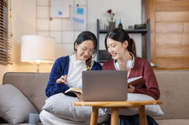 Genç, mutlu, gülümseyen, kulaklık takan iki Asyalı öğrenci üniversite kampüsünde ya da sanal ofiste bilgisayarla sohbet ediyorlar. Üniversiteli kız öğrenci uzaktan öğreniyor..