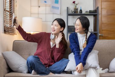Genç, mutlu, gülümseyen, kulaklık takan iki Asyalı öğrenci üniversite kampüsünde ya da sanal ofiste bilgisayarla sohbet ediyorlar. Üniversiteli kız öğrenci uzaktan öğreniyor..