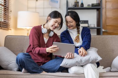 Genç, mutlu, gülümseyen, kulaklık takan iki Asyalı öğrenci üniversite kampüsünde ya da sanal ofiste bilgisayarla sohbet ediyorlar. Üniversiteli kız öğrenci uzaktan öğreniyor..