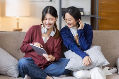 Genç, mutlu, gülümseyen, kulaklık takan iki Asyalı öğrenci üniversite kampüsünde ya da sanal ofiste bilgisayarla sohbet ediyorlar. Üniversiteli kız öğrenci uzaktan öğreniyor..