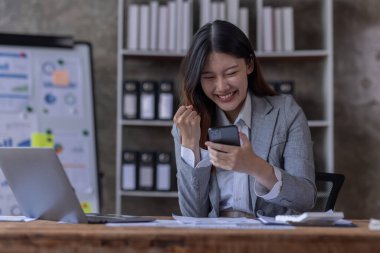 Bir ofis masası, vergi, rapor, muhasebe, istatistik ve analitik araştırma kavramında matematik finansmanı için hesap makinesi ve dizüstü bilgisayar kullanan Asyalı İş kadını