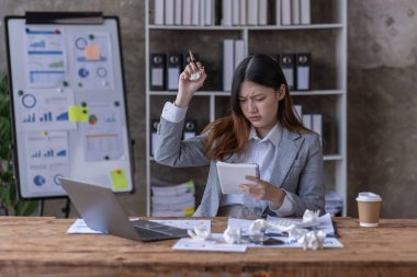 Bir ofis masası, vergi, rapor, muhasebe, istatistik ve analitik araştırma kavramında matematik finansmanı için hesap makinesi ve dizüstü bilgisayar kullanan Asyalı İş kadını