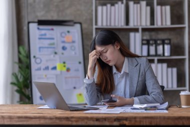 Bir ofis masası, vergi, rapor, muhasebe, istatistik ve analitik araştırma kavramında matematik finansmanı için hesap makinesi ve dizüstü bilgisayar kullanan Asyalı İş kadını