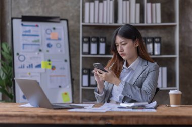 Bir ofis masası, vergi, rapor, muhasebe, istatistik ve analitik araştırma kavramında matematik finansmanı için hesap makinesi ve dizüstü bilgisayar kullanan Asyalı İş kadını