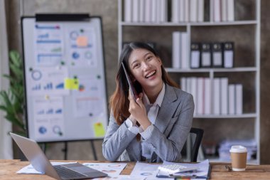 Bir ofis masası, vergi, rapor, muhasebe, istatistik ve analitik araştırma kavramında matematik finansmanı için hesap makinesi ve dizüstü bilgisayar kullanan Asyalı İş kadını