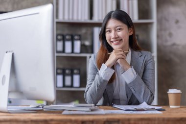 Bir ofis masası, vergi, rapor, muhasebe, istatistik ve analitik araştırma kavramında matematik finansmanı için hesap makinesi ve dizüstü bilgisayar kullanan Asyalı İş kadını
