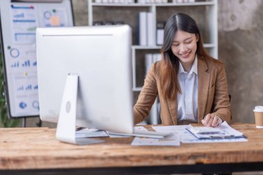 Bir ofis masası, vergi, rapor, muhasebe, istatistik ve analitik araştırma kavramında matematik finansmanı için hesap makinesi ve dizüstü bilgisayar kullanan Asyalı İş kadını