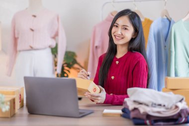 İnternette kıyafet satan Asyalı kadın KOBİ 'ler, evde telefon ve dizüstü bilgisayarla müşterilerin sorularını cevaplıyor, küçük işletme girişimciliği, Çevrimiçi ticaret, KOBİ konsepti.