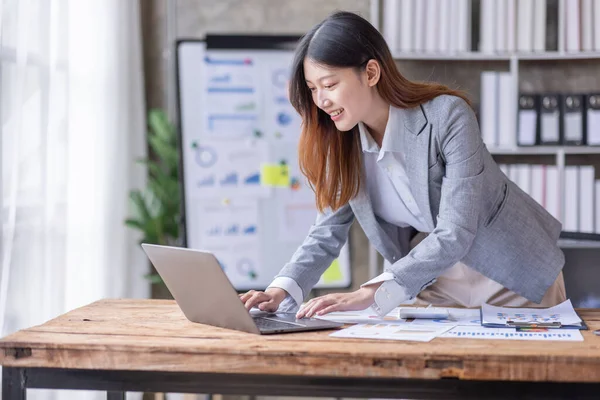 Bir ofis masası, vergi, rapor, muhasebe, istatistik ve analitik araştırma kavramında matematik finansmanı için hesap makinesi ve dizüstü bilgisayar kullanan Asyalı İş kadını