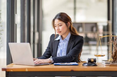 justice and law concept. Lawyer office. Statue of Justice with scales and lawyer Asian Woman working on a laptop. Legal law, advice and justice concept.