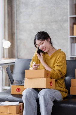 Startup SME small business entrepreneur of freelance Asian woman using a laptop with box Cheerful success Asian woman her hand lifts up online marketing packaging box and delivery SME idea concept