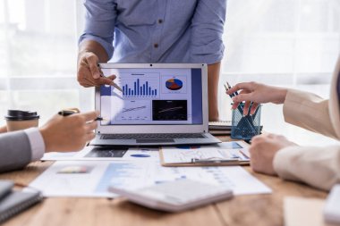 Group of confident business people point to graphs and charts to analyze market data, balance sheet, account, net profit to plan new sales strategies to increase production capacity.