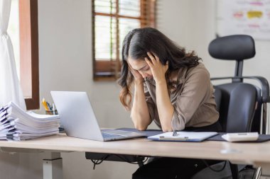 Asian indian women are stressed while working on laptop, Tired asian businesswoman with headache at office, feeling sick at work copy space in workplace an home office.