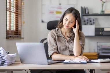 Asian indian women are stressed while working on laptop, Tired asian businesswoman with headache at office, feeling sick at work copy space in workplace an home office.