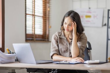 Asian indian women are stressed while working on laptop, Tired asian businesswoman with headache at office, feeling sick at work copy space in workplace an home office.