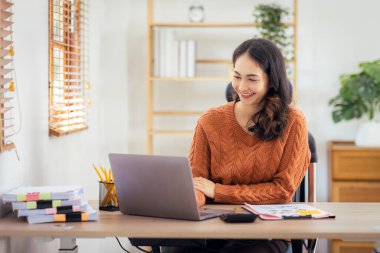 Freelancer Asian businesswoman Accounting work at home using calculating income-expenditure and analyzing real estate investment data report Financial and Documents tax systems concept.