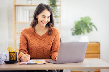 Freelancer Asian businesswoman Accounting work at home using calculating income-expenditure and analyzing real estate investment data report Financial and Documents tax systems concept.