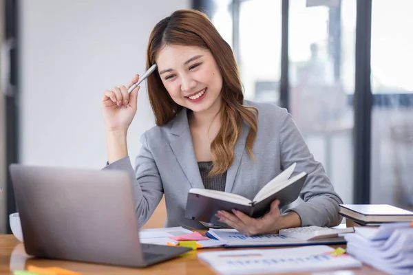 Young asian business woman manager accounting analyst checking bills, analyzing sales statistics management, taxes financial data documents or marketing report papers working in office using laptop.
