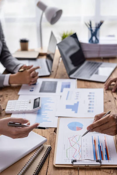 Group of confident business people point to graphs and charts to analyze market data, balance sheet, account, net profit to plan new sales strategies to increase production capacity.