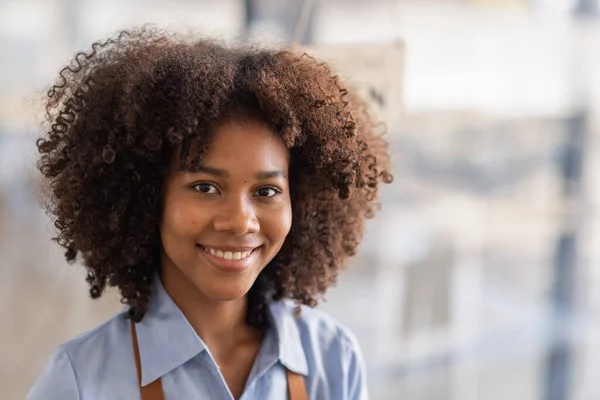 Happy waitress standing at restaurant entrance. Portrait of african american business woman attend new customers in her coffee shop. Happy woman owner showing open sign in her small business shop.