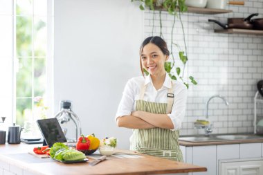 Portrait of attractive asian japanese woman in kitchen at home, young girl browsing website on tutor cooking class and doing for kitchen, cutting vegetables, cooking, cooking concept.