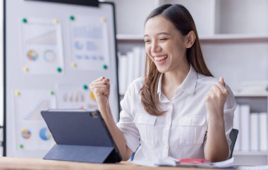 Happy Asian woman holding a smartphone and winning the prize, asian female happy excited in workplace office