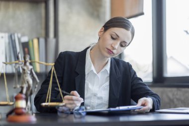 Statue of Justice and female lawyer in suit at workplace with laptop, gavel and femida in office. Law, legal services, advice, Justice and real estate concept.