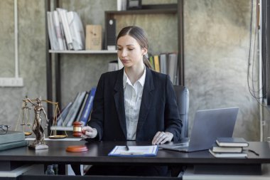 Statue of Justice and female lawyer in suit at workplace with laptop, gavel and femida in office. Law, legal services, advice, Justice and real estate concept.