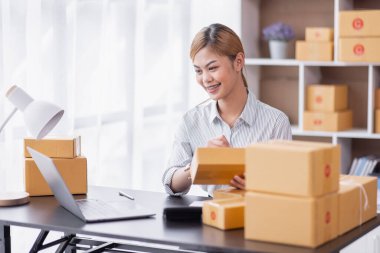 Portrait of Starting Asian female small businesses owners SME entrepreneur working at home, online marketing, packing boxes, SME sellers, concept, e-commerce team, online sales.