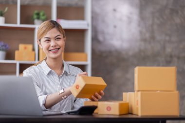 Portrait of Starting Asian female small businesses owners SME entrepreneur working at home, online marketing, packing boxes, SME sellers, concept, e-commerce team, online sales.