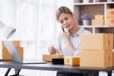 Portrait of Starting Asian female small businesses owners SME entrepreneur working at home, online marketing, packing boxes, SME sellers, concept, e-commerce team, online sales.