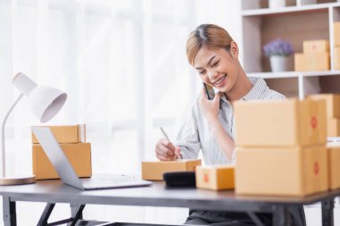 Portrait of Starting Asian female small businesses owners SME entrepreneur working at home, online marketing, packing boxes, SME sellers, concept, e-commerce team, online sales.