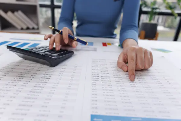 Muhasebe bankacılığı konsepti. Finans işleriyle ilgilenen bir iş kadını ve ofis masraflarını hesaplayan bir masa. Hesap makinesi ve mali muhasebe kullanan bir kadın..