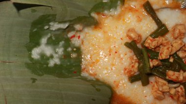 indonesian food poridge in a banana leaf background with tempe and various red seasoning