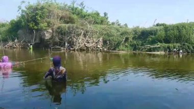 The activity of several people fishing in the river by diving in, on a hot afternoon