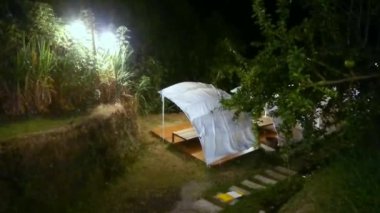 4k gizli mücevher, ışıkların altında, ormanın içinde bir turist çadırı gece nehir kenarında, dinlenmek için serin ve sessiz bir yer.